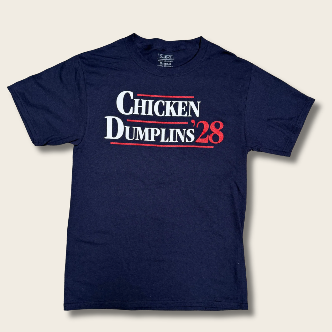 A navy blue short-sleeve t-shirt with a graphic print reading 'CHICKEN DUMPLINS '28' in white and red text on the chest, displayed flat against a light beige background.