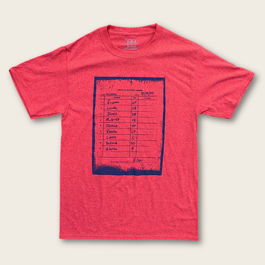 A heathered red t-shirt with a dark blue graphic print of a vintage scorecard on the front, displayed flat against a light beige background.