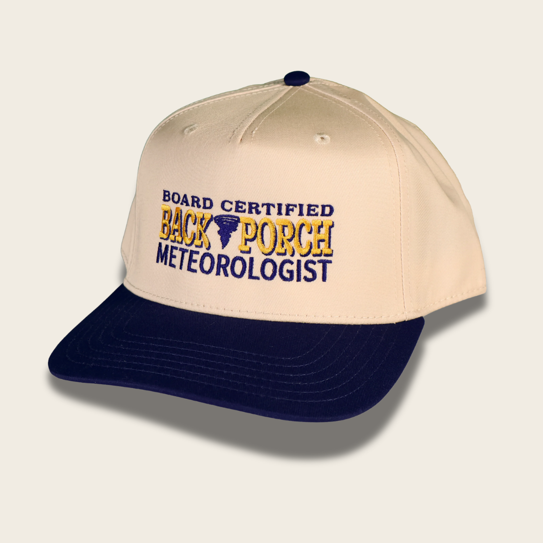 A beige and navy blue baseball cap with embroidered text reading 'BOARD CERTIFIED BACK PORCH METEOROLOGIST' on the front panel.