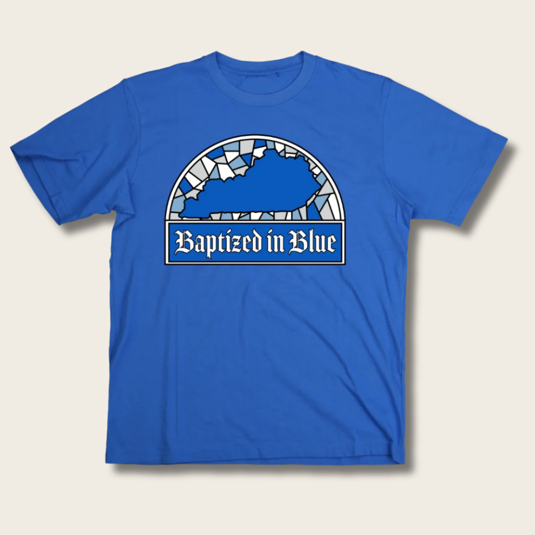 A royal blue short-sleeve t-shirt with a graphic on the chest depicting the state of Kentucky in a stained-glass style above the text 'Baptized in Blue' in a white banner.