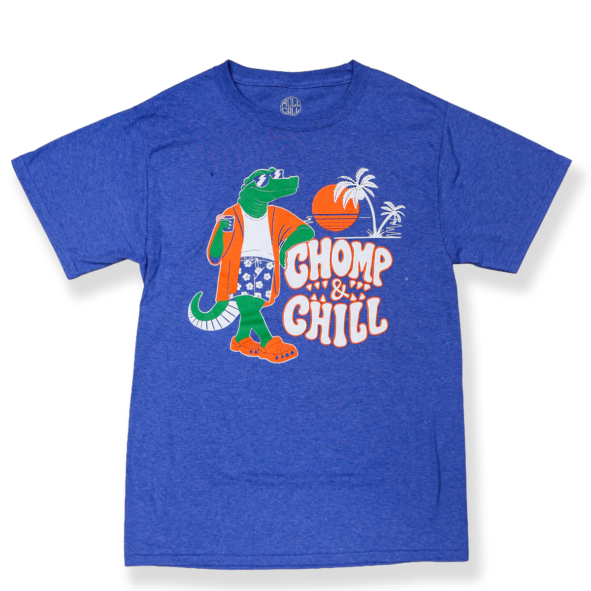 A blue shirt with a graphic of an alligator holding a beverage while wearing hawaiian shorts and crocs, on a sunset beach with the white and orange text "CHOMP & CHILL."