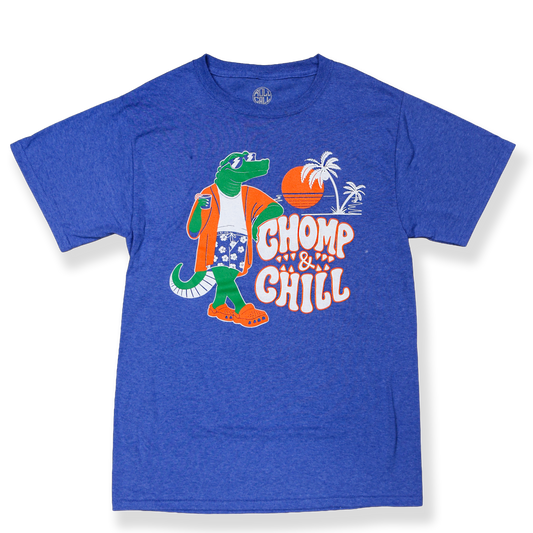 A blue shirt with a graphic of an alligator holding a beverage while wearing hawaiian shorts and crocs, on a sunset beach with the white and orange text "CHOMP & CHILL."
