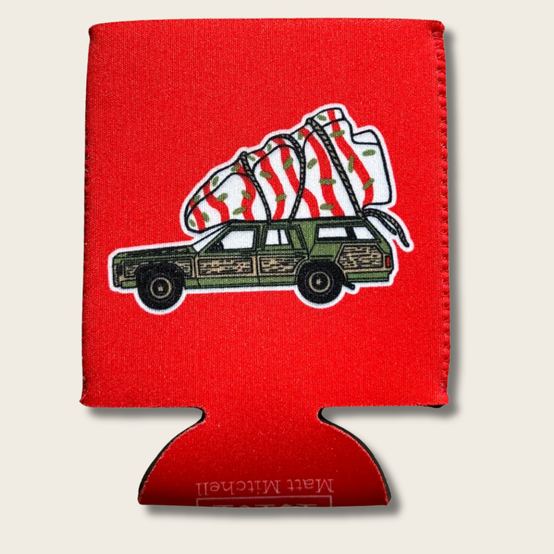 A red can cooler sleeve featuring a graphic of a green wood-paneled station wagon carrying a striped Christmas tree, shown on a light beige background.