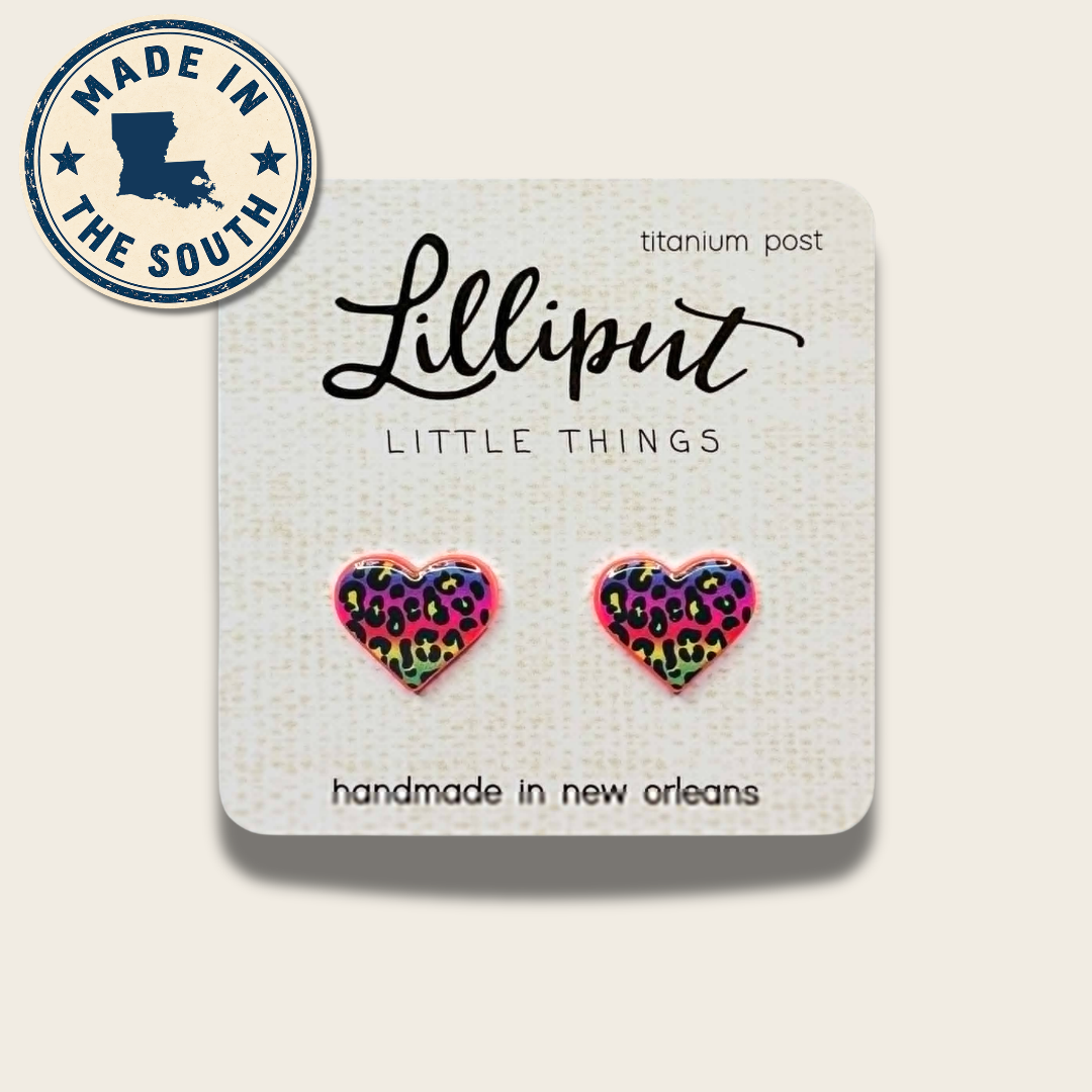 A pair of heart-shaped stud earrings with a colorful leopard print pattern on a white display card. The card has the brand name 'Lilliput' and 'LITTLE THINGS' printed on it, along with a circular 'MADE IN THE SOUTH' badge in the top left corner.