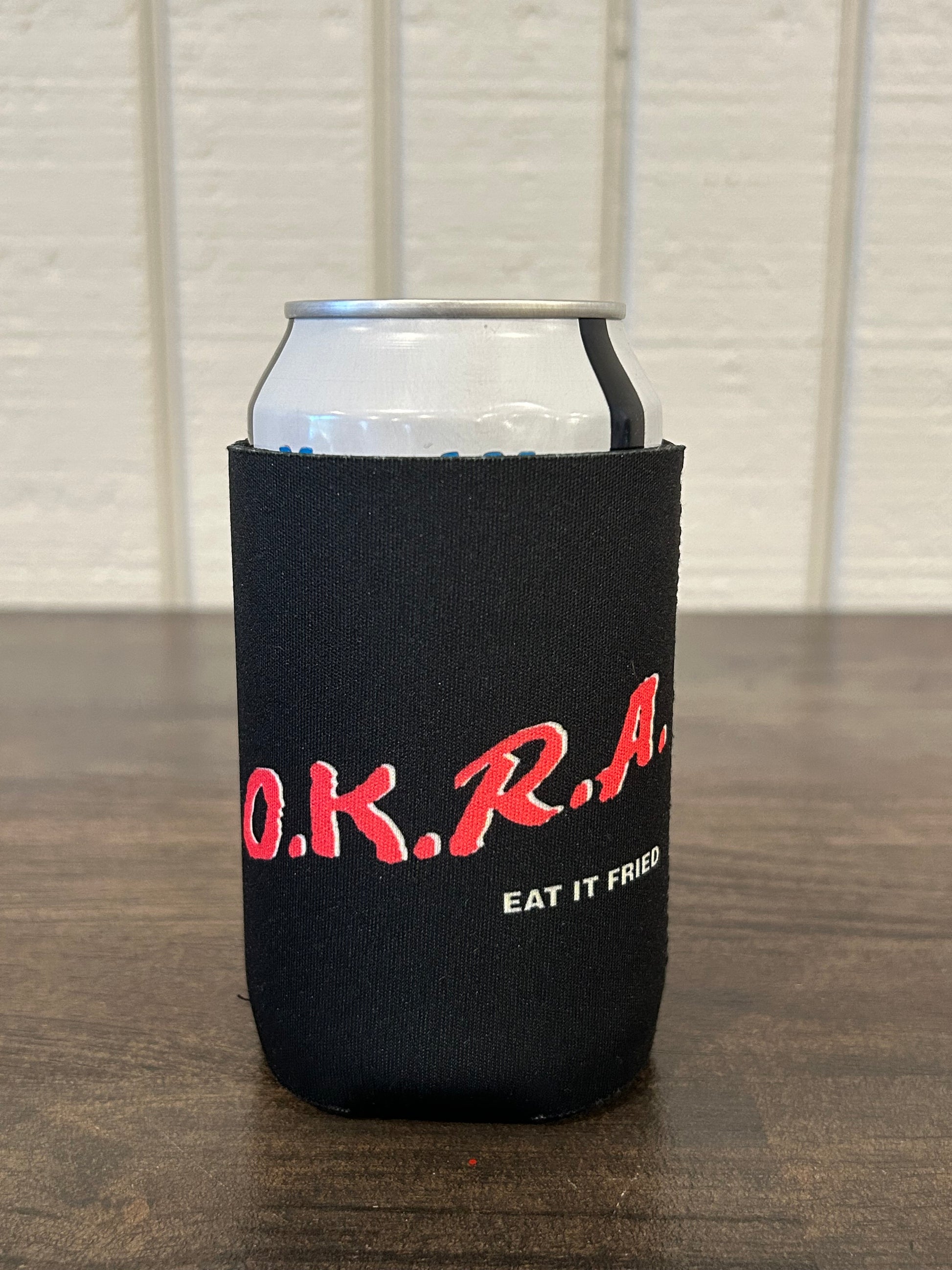 Black can cooler with red text depicting DARE parody "O.K.R.A." 