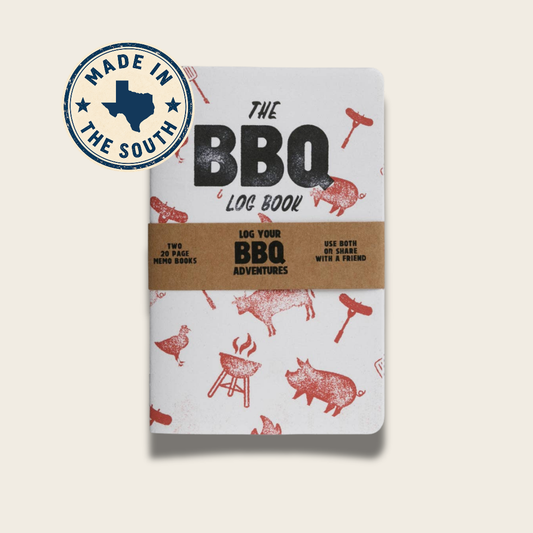 The BBQ Log Book with a white cover decorated with red barbecue illustrations and a brown paper band around the middle. A blue circular 'Made in the South' badge is shown in the top left corner.